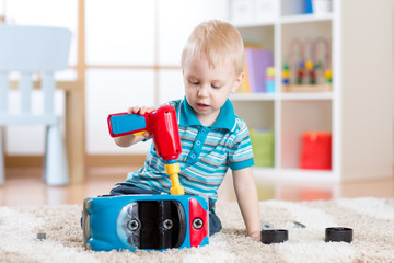 Child little boy repairs toy car indoor