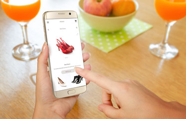Wall Mural - Online shopping with smart phone. Isolated phone in woman hand. Buying women shoes on online store.