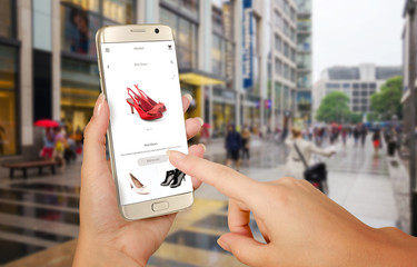 Wall Mural - Online shopping with smart phone. Phone in woman hand. Buying women shoes on online store. Street walk and visiting shopping malls.