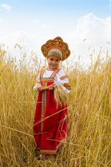 Wall Mural - Girl in Russian national sarafan and a kokoshnik standing in a wheat field in summer day