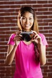 © WavebreakmediaMicro - Smiling asian woman taking picture with camera