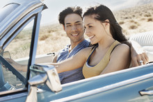 A Young Couple, Man And Woman In A Pale Blue Convertible On The Open Road 