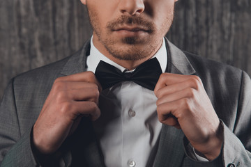 Wall Mural - Close up portrait of young man fastening a bow-tie on his shirt