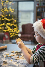 A Boy In A Santa Hat Making Christmas Biscuits, Cutting Out Shapes, 