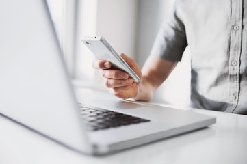 Wall Mural - Close up of a man using mobile smart phone, a business man hands busy using cell phone at office desk