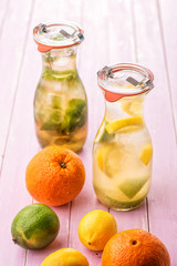 set of two summer lemonade with ice and fruit like lemon, lime and mint leaves, summer drink with soda on pink background