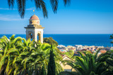 Fototapeta Miasto - the belfry and church's roof is hiding behind the palms, sanremo, italy