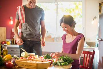 Trendy couple cooking vegetables from the market in the kitchen