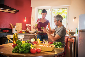 Nice couple cooking together vegetables in retro red kitchen