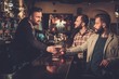 © Nejron Photo - Cheerful old friends drinking draft beer at bar counter in pub.