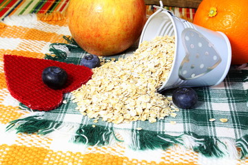Wall Mural - Dry rolled oatmeal flakes in heart  bucket with blueberry heart apple orange 