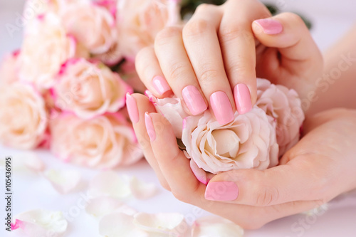 Fotomural Hands of a woman with pink manicure on nails and roses