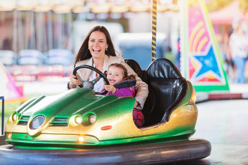 Mother and daughter in bumper car at fun fair