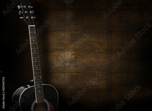 Plakat Czarna gitara akustyczna na ciemnożółtym drewnianym tle.