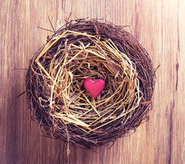 red heart with nest on old shabby wooden background