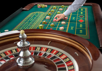 Roulette and piles of gambling chips on a green table. 