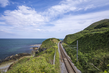 Railway through stone rocks mountain at Irish seacoast. Bray, Greystone