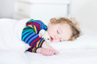 © famveldman - Adorable toddler girl taking a nap in a white bed