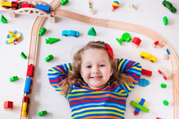 Wall Mural - Little girl playing with wooden trains