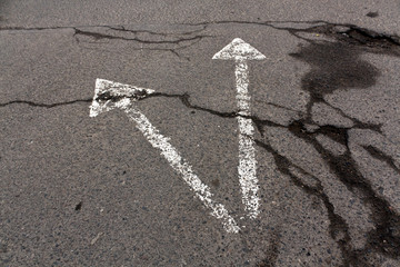 Two white arrows on cracked asphalt texture.