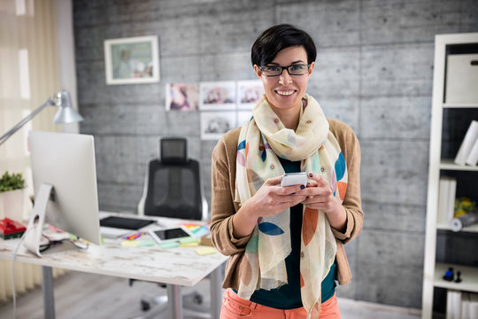 smiling designer texting on smart phone.