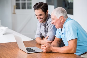 Wall Mural - Smiling father and son using laptop 