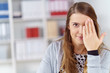 © contrastwerkstatt - lächelnde frau im büro hält die hand vor ein auge