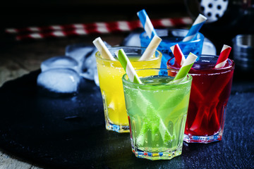 Colorful cocktails with straws on a dark background, selective f