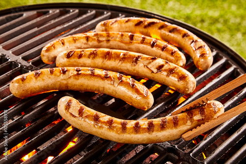 Fotografie, Obraz Pork sausages grilling on a portable BBQ