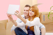 © Philipimage - Happy couple sitting on the floor taking selfie in their new hou