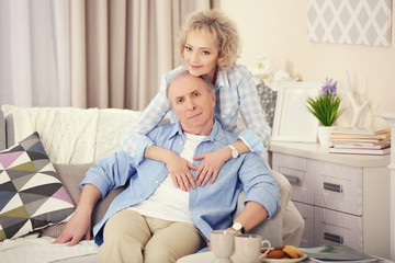 Mature couple sitting together  on a sofa at home