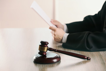 Wall Mural - judge reading document with gavel at wooden table in courtroom