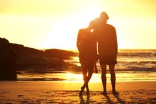 Loving Couple Standing By The Beach Looking At Sunset