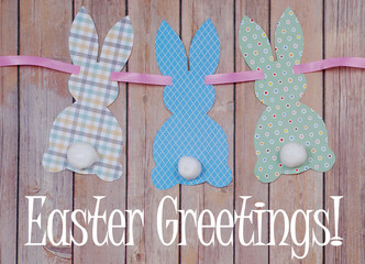 Cute craft paper cutout bunny shapes on natural background with cotton swab tails for Easter