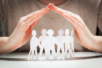 paper people under hands in gesture of protection.. concept of insurance