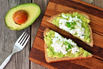 Wall Mural - Avocado toast with egg whites and pea shoots on wooden board, overhead view