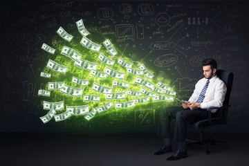 Businessman sitting in chair holding tablet with dollar bills co