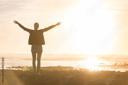 Fotografía Silhouette of free woman enjoying freedom feeling happy at beach at sunset