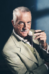 Wall Mural - Cigar smoking retro 1940 senior businessman. Studio shot.