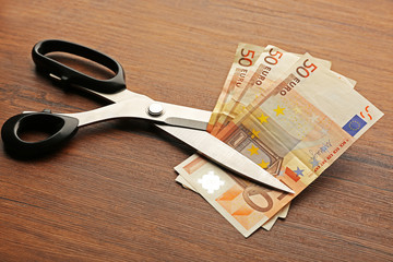 Poster - Concept of spending money - scissors cut money on wooden background