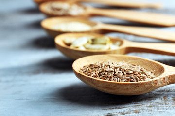 Wall Mural - Various seeds in wooden spoons on blue background, closeup