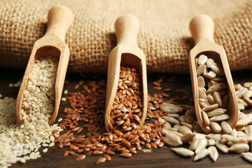 Wall Mural - Sesame, flax and sunflower seeds in wooden spoons on table, closeup