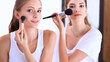 © shefkate - Beautiful girls looking in the mirror and applying cosmetic with a big brush
