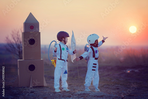 Cuadros en Lienzo Dos adorables niños, jugando en el parque en la puesta del sol, vestidos como un