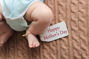 Newborn baby feet on knitted background, mother's day concept