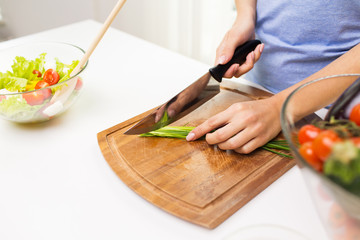 Wall Mural - close up of woman chopping green onion with knife