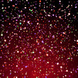 colorful glitter in front of a dark background with a red light from below