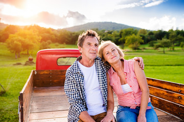 Senior couple sitting in back of red pickup truck