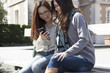 © Monet - Two women looking at a smart phone with a laugh