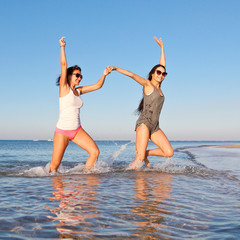 Two young slender girl fun running on the beach